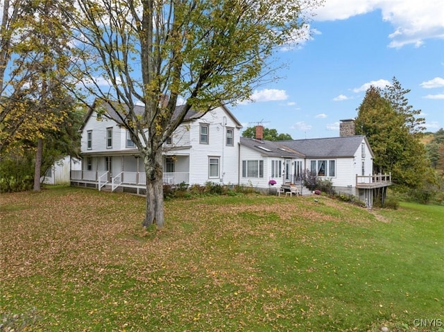 view of front facade with covered porch, a chimney, and a front yard