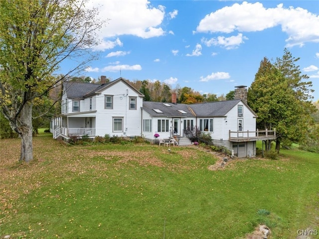 rear view of property with a yard, a chimney, and an attached garage