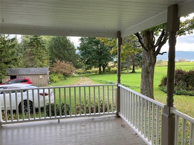 wooden deck featuring an outbuilding and a yard