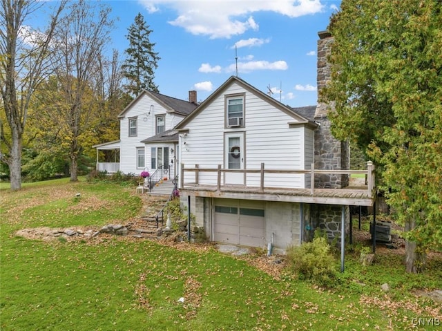 rear view of house with an attached garage, cooling unit, a lawn, a wooden deck, and a chimney