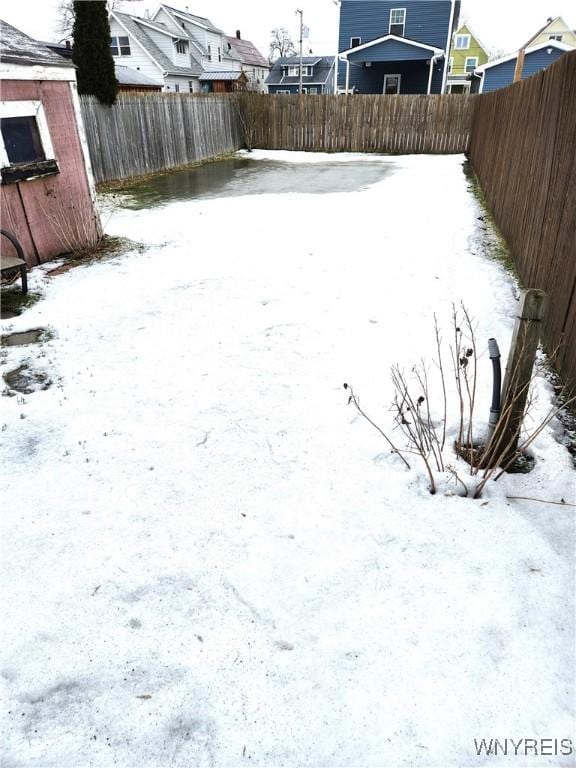 yard layered in snow with a fenced backyard