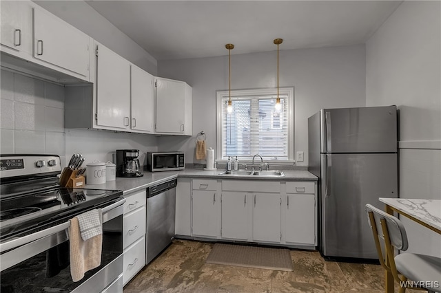 kitchen featuring stainless steel appliances, a sink, white cabinetry, hanging light fixtures, and light countertops