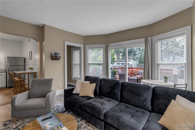 living area with baseboards, arched walkways, and wood finished floors