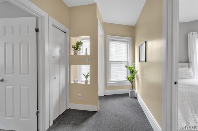 interior space featuring dark colored carpet and baseboards