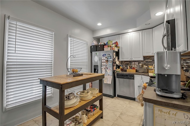 kitchen with stainless steel appliances, dark countertops, marble finish floor, and backsplash