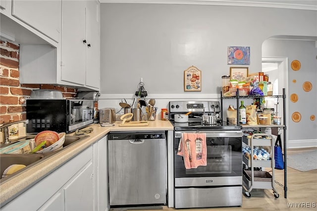 kitchen featuring light countertops, light wood-style flooring, appliances with stainless steel finishes, white cabinets, and a sink