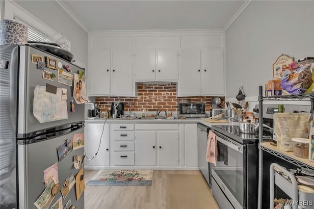 kitchen featuring white cabinetry, stainless steel appliances, light countertops, and ornamental molding