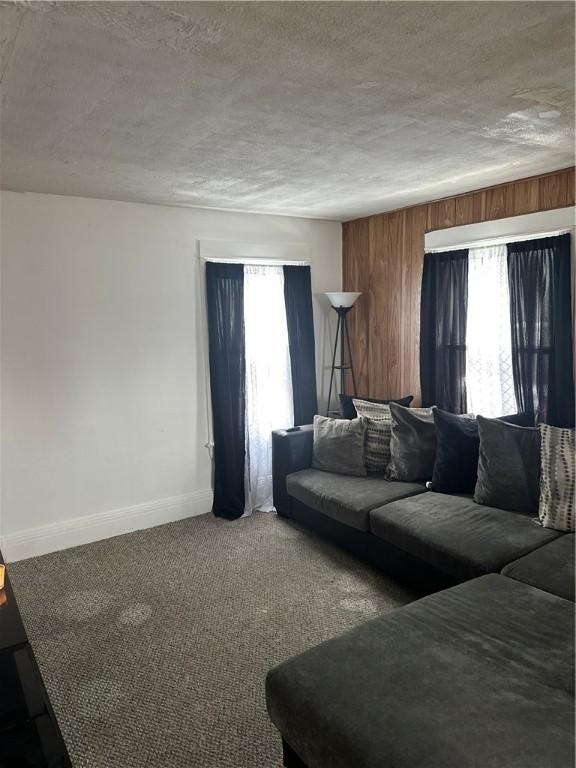 unfurnished living room with a textured ceiling, baseboards, and carpet flooring