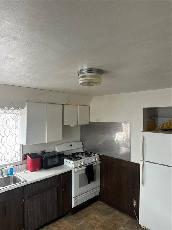 kitchen with white appliances, white cabinets, light countertops, dark brown cabinets, and a sink