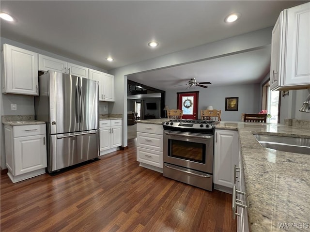 kitchen featuring appliances with stainless steel finishes, a sink, dark wood finished floors, and white cabinetry