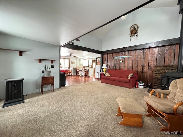 living area featuring ceiling fan, high vaulted ceiling, carpet, and a wood stove