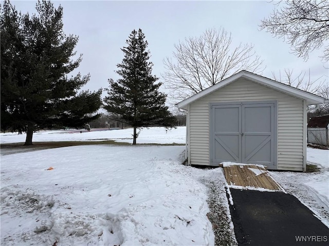 snow covered structure featuring an outdoor structure and a shed