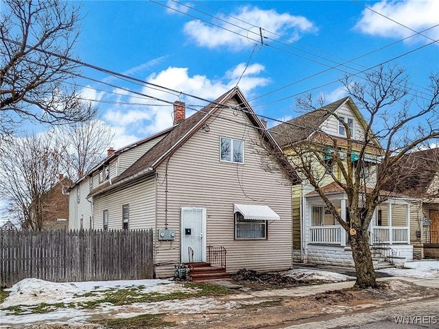 view of front of house featuring a chimney and fence