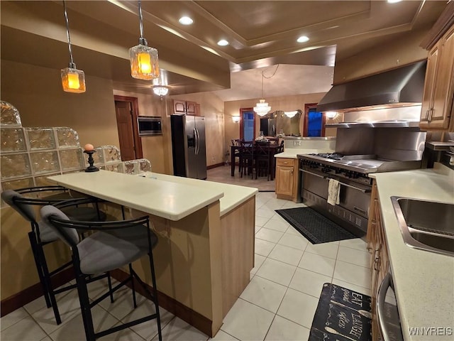 kitchen featuring appliances with stainless steel finishes, a peninsula, light countertops, under cabinet range hood, and a sink