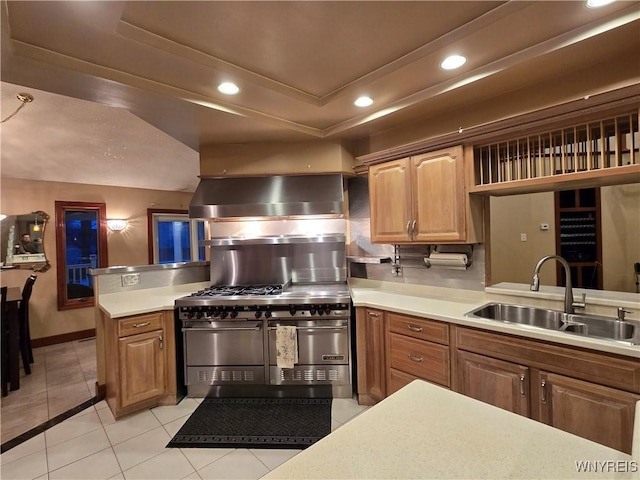 kitchen with double oven range, a tray ceiling, light countertops, and a sink