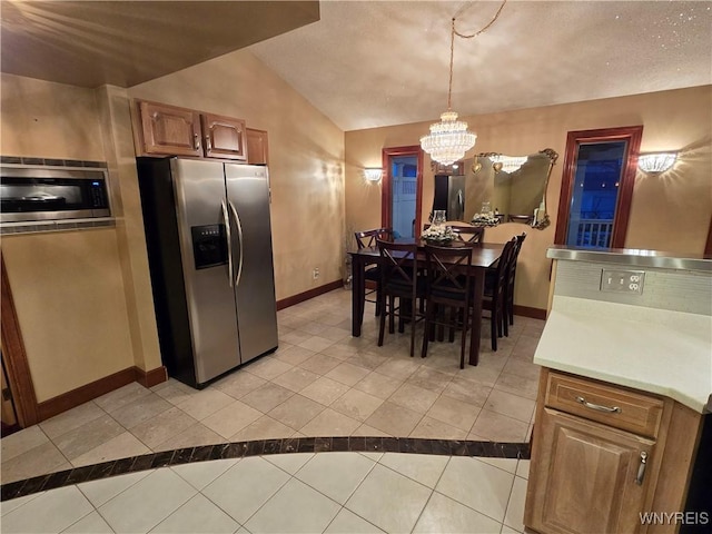 kitchen with lofted ceiling, light tile patterned floors, baseboards, and appliances with stainless steel finishes