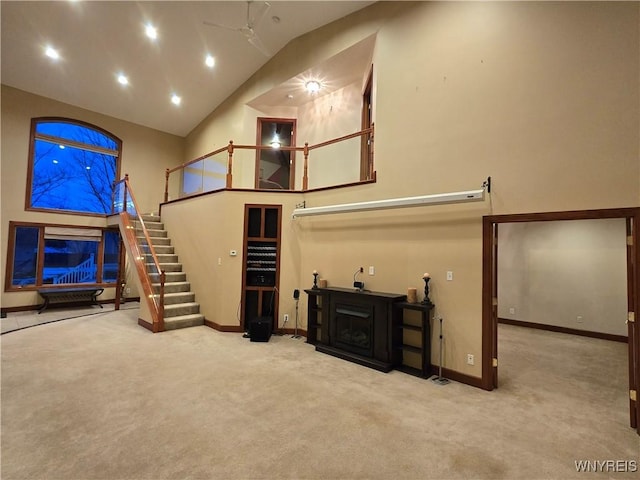 interior space featuring carpet floors, a fireplace, recessed lighting, high vaulted ceiling, and stairs