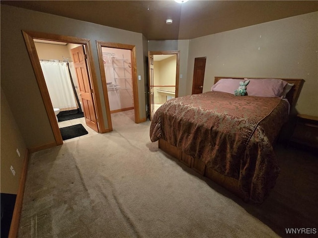 bedroom featuring a closet, a spacious closet, light carpet, connected bathroom, and baseboards