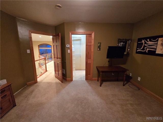 hallway with baseboards and light colored carpet