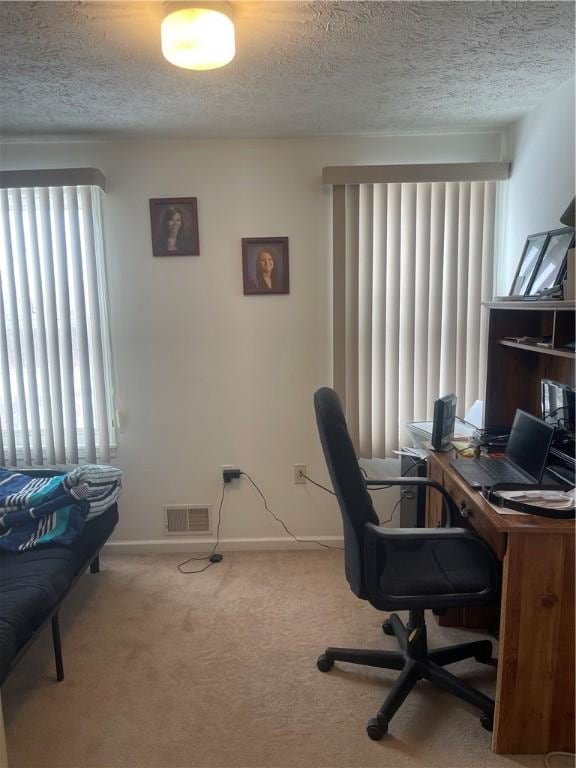 carpeted home office featuring baseboards, visible vents, and a textured ceiling