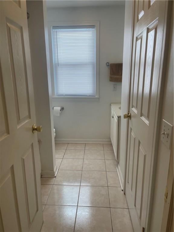 bathroom with toilet, tile patterned flooring, baseboards, and vanity