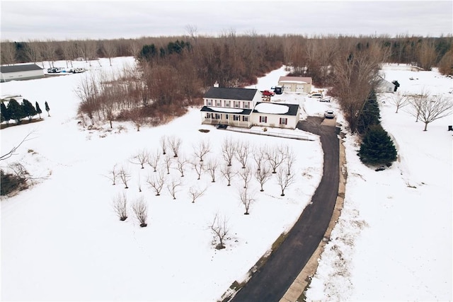 snowy aerial view featuring a wooded view