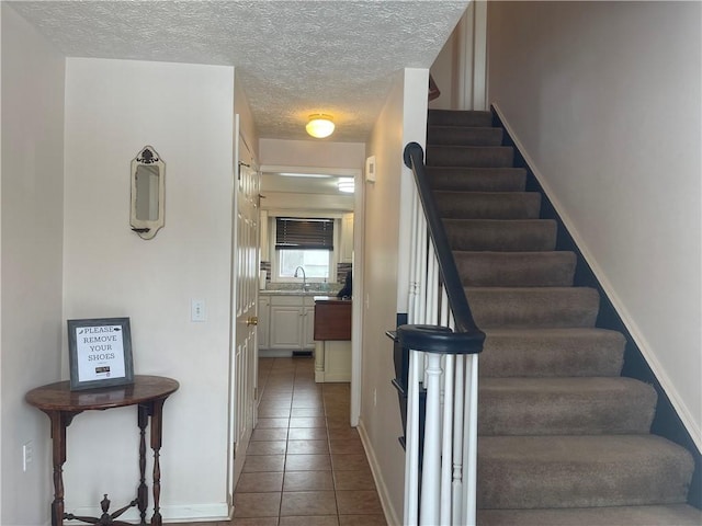 stairway featuring baseboards, a textured ceiling, and tile patterned floors