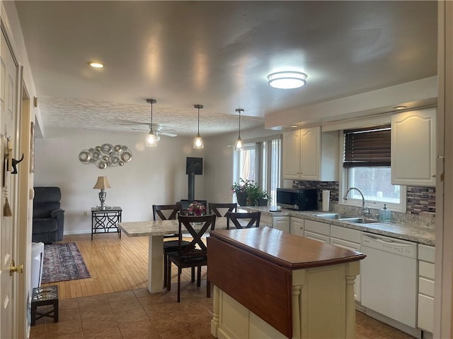 kitchen with tile patterned flooring, a sink, a wealth of natural light, dishwasher, and stainless steel microwave