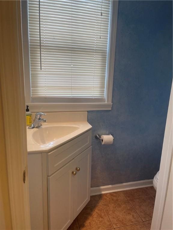 half bathroom featuring toilet, vanity, baseboards, and tile patterned floors