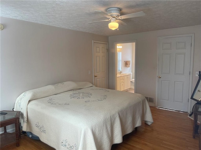 bedroom with a ceiling fan, a textured ceiling, visible vents, and wood finished floors