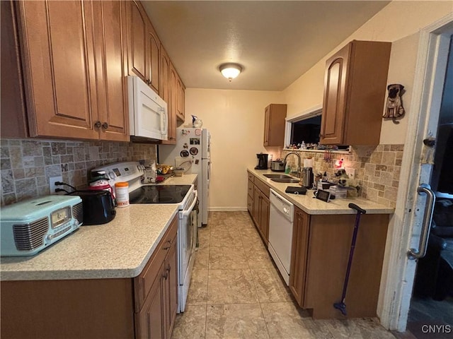 kitchen featuring white appliances, a sink, baseboards, light countertops, and decorative backsplash