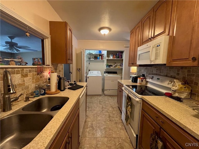 kitchen featuring white appliances, a sink, a ceiling fan, tasteful backsplash, and washer and clothes dryer