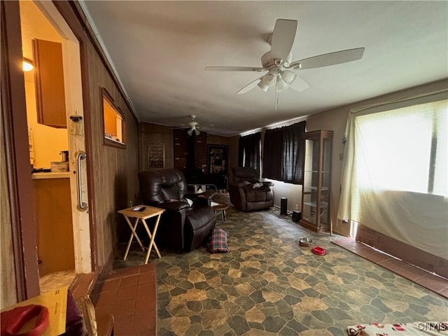 living area with a ceiling fan, stone finish flooring, and wooden walls