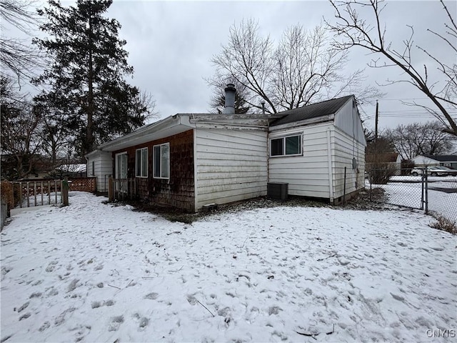 view of snow covered exterior with fence and a chimney