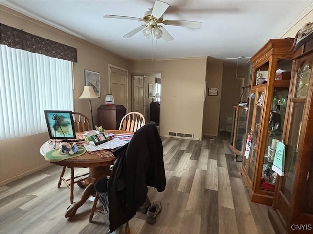 dining room featuring baseboards, wood finished floors, visible vents, and a ceiling fan