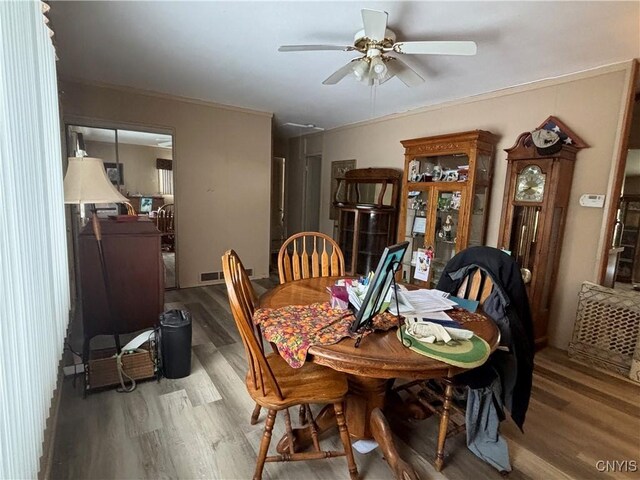 dining area with light wood finished floors, crown molding, visible vents, and a ceiling fan