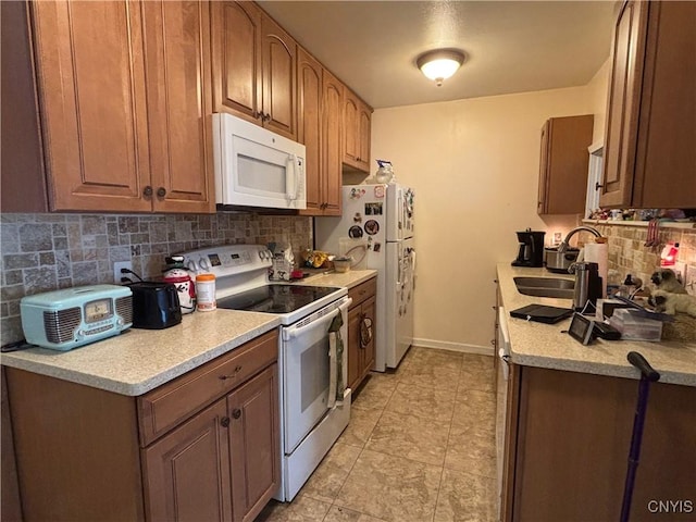 kitchen with white appliances, tasteful backsplash, baseboards, light countertops, and a sink