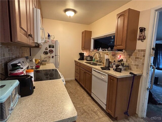 kitchen featuring white appliances, light countertops, and a sink