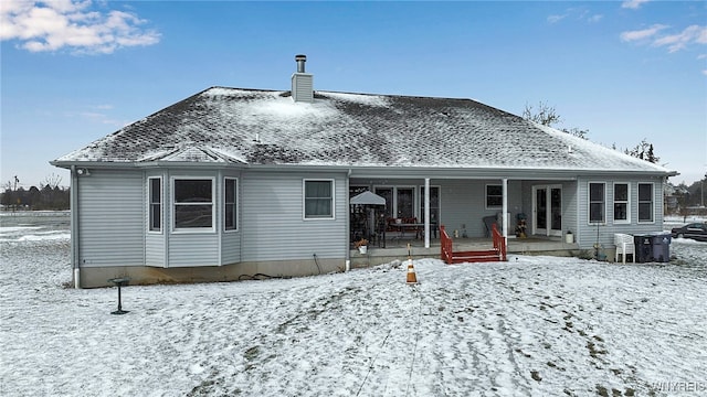 snow covered back of property with a chimney