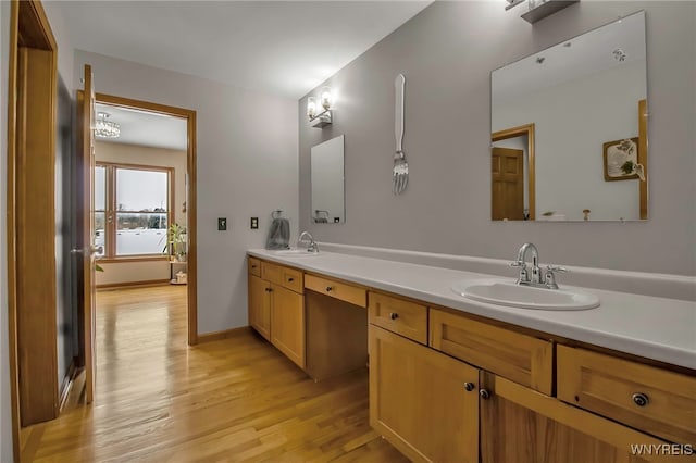 bathroom with a sink, baseboards, wood finished floors, and double vanity