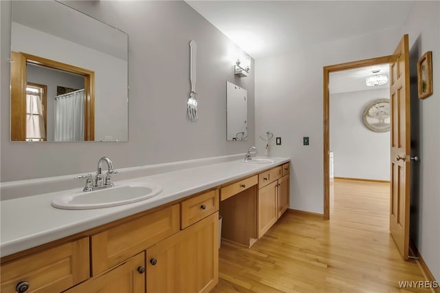 full bathroom featuring a sink, baseboards, wood finished floors, and double vanity