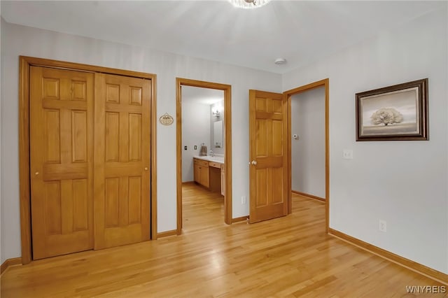 unfurnished bedroom featuring a closet, baseboards, and light wood finished floors