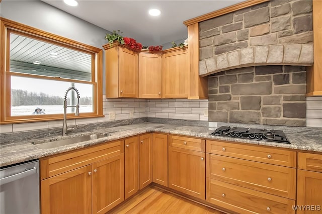 kitchen with black gas stovetop, a sink, backsplash, light stone countertops, and dishwasher