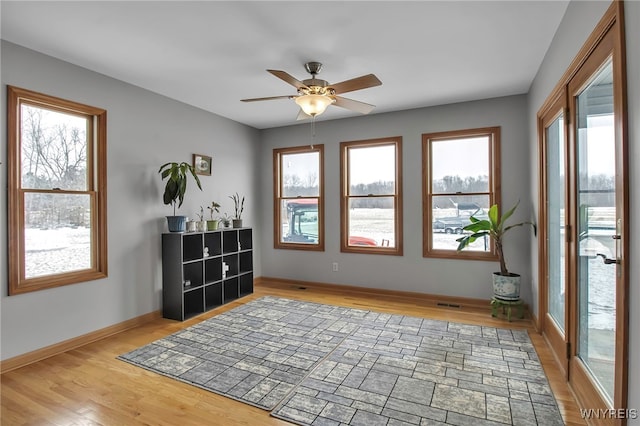 sitting room with visible vents, light wood-style flooring, baseboards, and ceiling fan