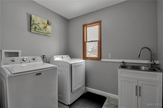 laundry area featuring cabinet space, separate washer and dryer, baseboards, and a sink