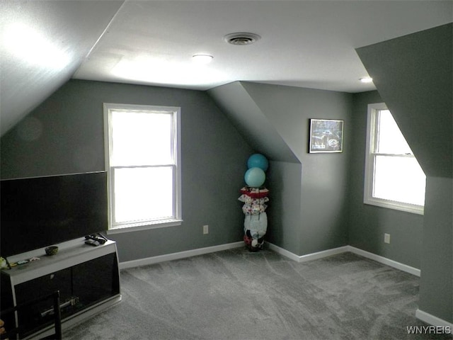 additional living space with visible vents, carpet floors, baseboards, and vaulted ceiling