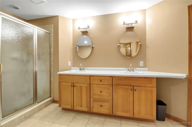 full bathroom featuring tile patterned flooring, double vanity, a stall shower, and a sink