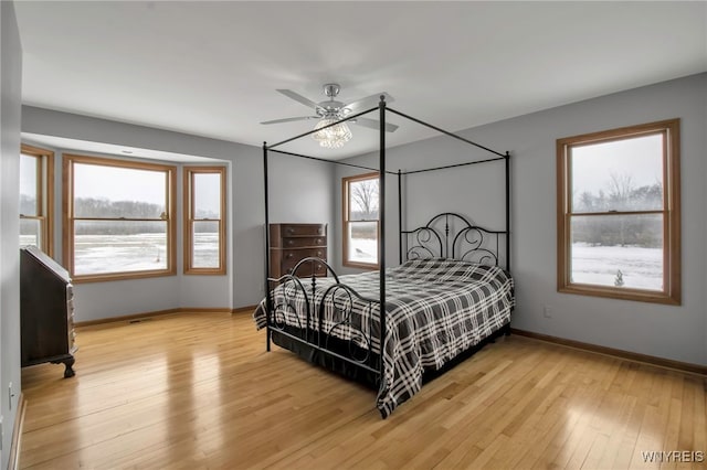 bedroom with ceiling fan, baseboards, and light wood-style flooring