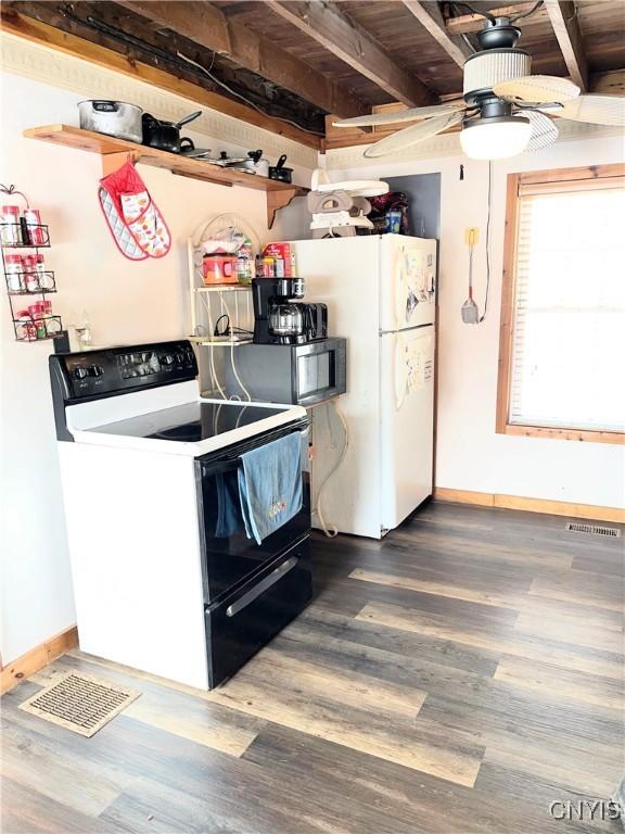 kitchen with dark wood-style flooring, range with electric stovetop, visible vents, freestanding refrigerator, and baseboards