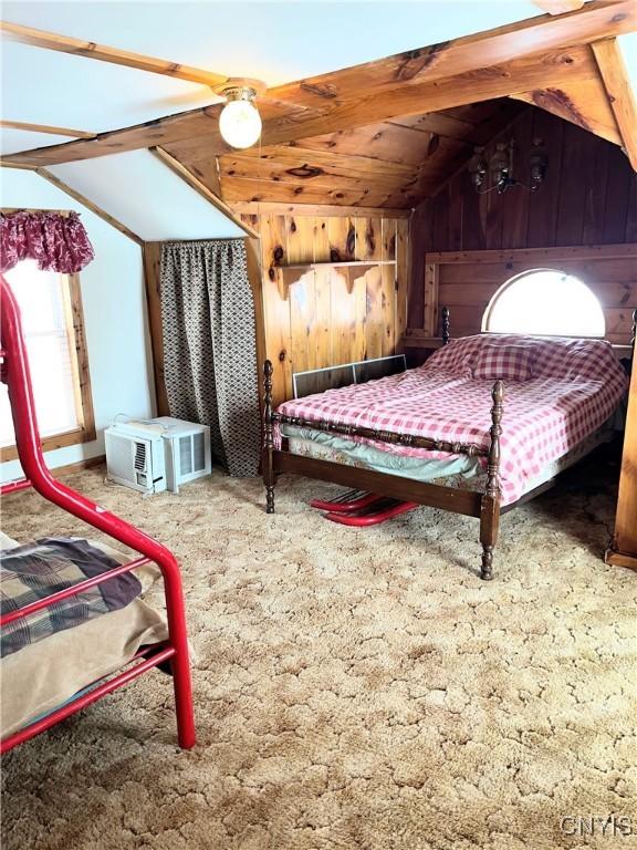 carpeted bedroom with wood walls and vaulted ceiling